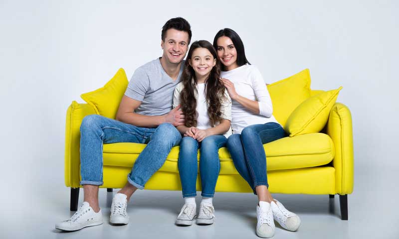 Family of three on a yellow couch.